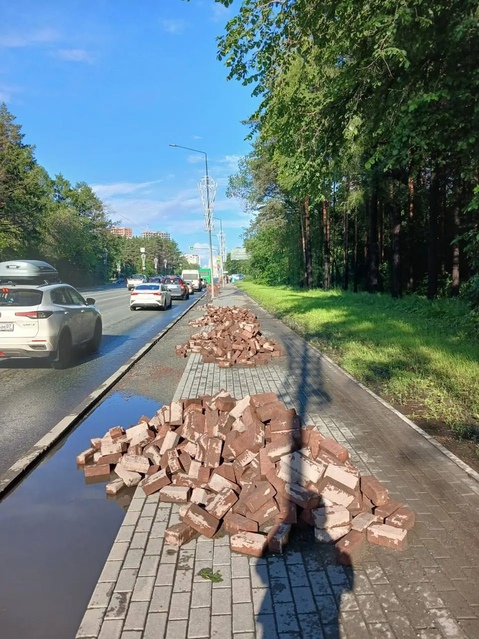 На улице Худякова укладывают новую «велополосу» между остановкой «Городской пляж» и подъездной дорогой к лесной резиденции — при этом пешеходов мало, а по центру тротуара стоят фонари.